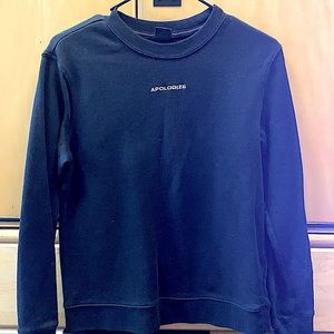 A black crew neck sweater. Wording “APOLOGIZE”
